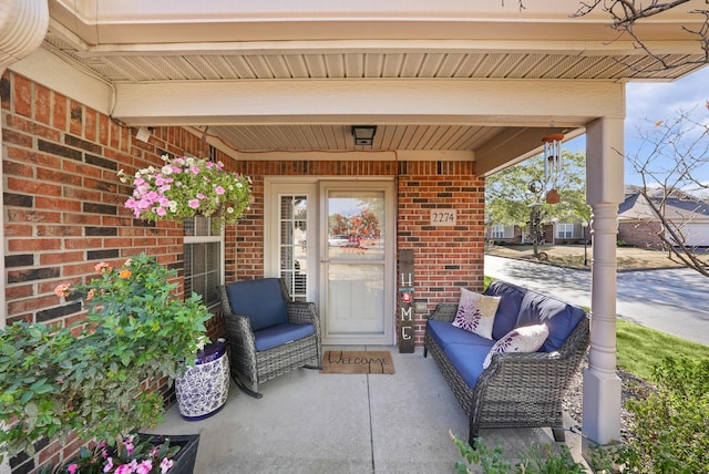 property entrance with covered porch, brick siding, and an outdoor hangout area