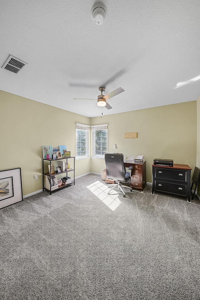 office space with visible vents, a ceiling fan, a textured ceiling, carpet, and baseboards