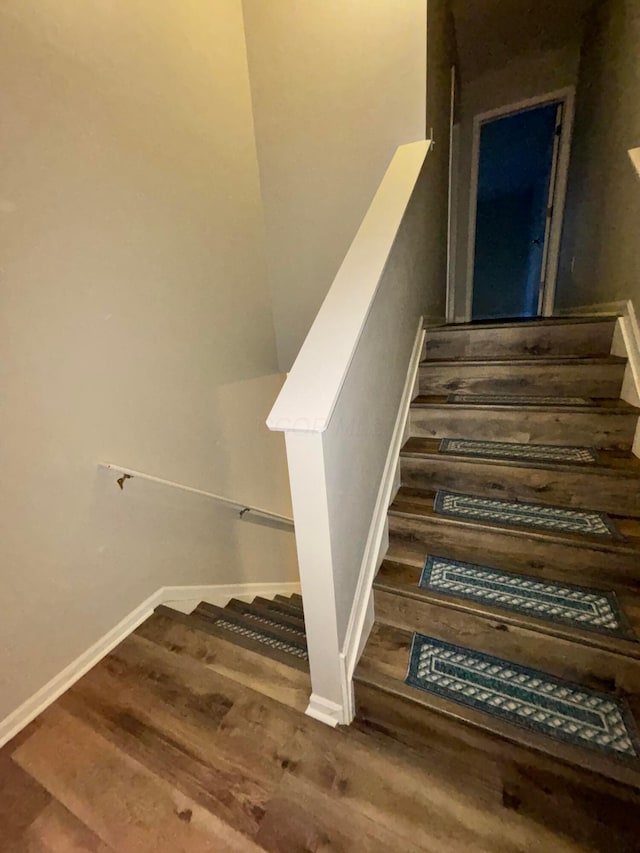 staircase featuring baseboards and wood finished floors