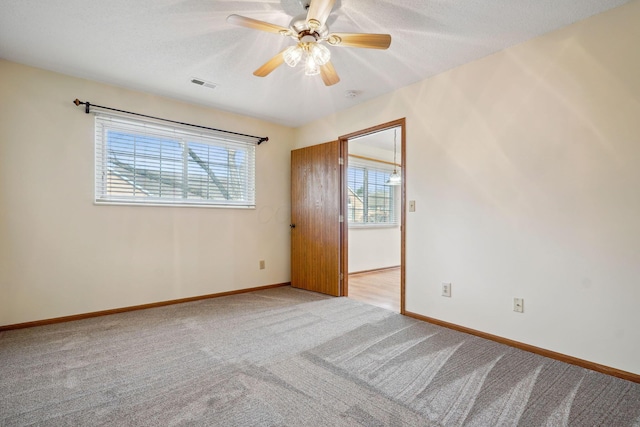 spare room with baseboards, visible vents, carpet floors, ceiling fan, and a textured ceiling