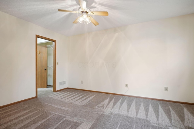 carpeted spare room with visible vents, a ceiling fan, and baseboards