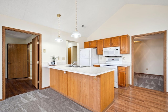 kitchen with light countertops, brown cabinets, a peninsula, white appliances, and a sink