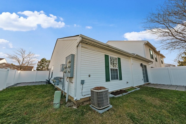 view of side of property with central AC unit, a lawn, and a fenced backyard