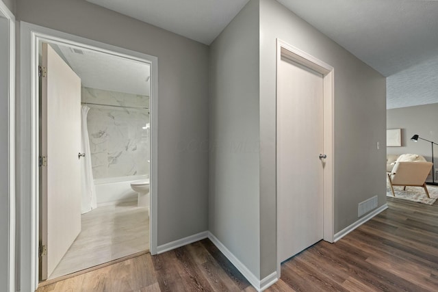 hallway featuring wood finished floors, visible vents, and baseboards