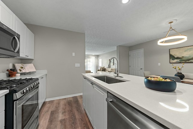 kitchen featuring light countertops, appliances with stainless steel finishes, dark wood-style floors, white cabinetry, and a sink