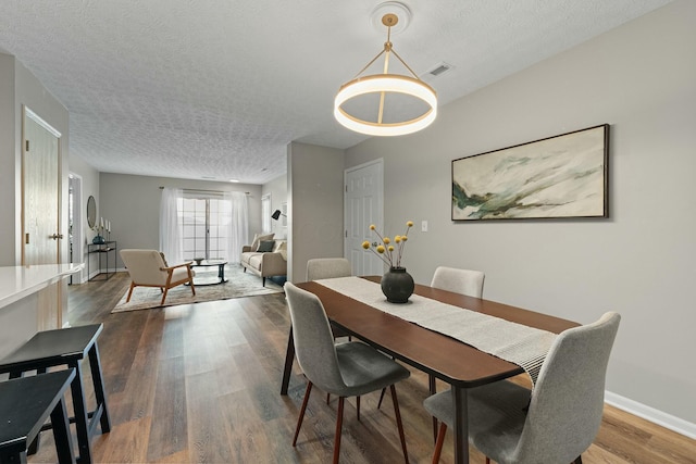 dining area featuring visible vents, baseboards, a textured ceiling, and dark wood-style flooring