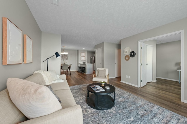 living room with baseboards, a textured ceiling, and wood finished floors