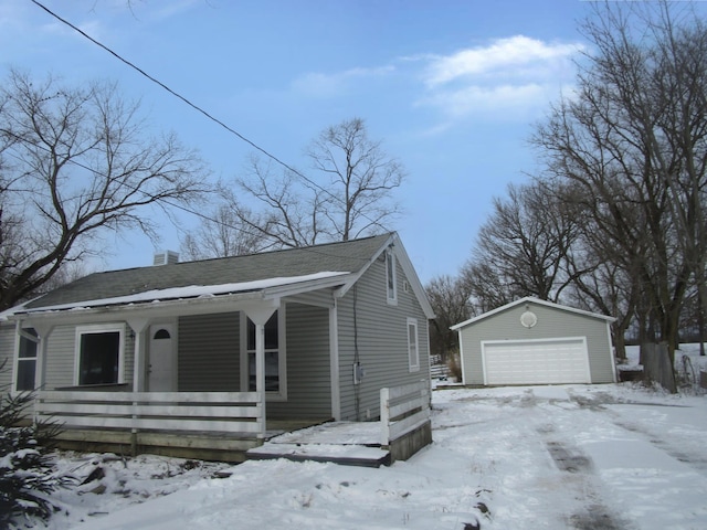 view of front of home featuring an outbuilding, covered porch, a chimney, and a detached garage