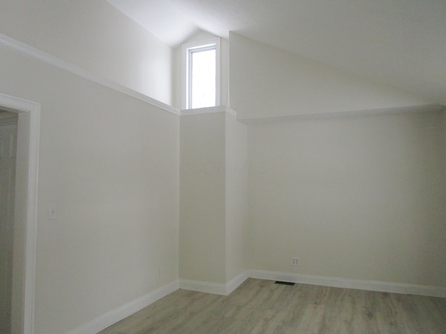 empty room featuring baseboards, lofted ceiling, and light wood finished floors