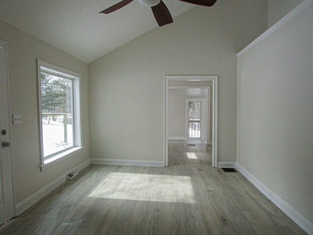 unfurnished room with visible vents, baseboards, lofted ceiling, and wood finished floors