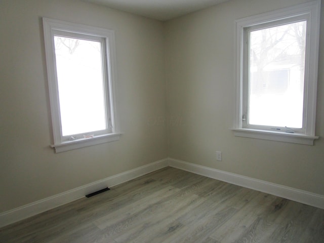 spare room with visible vents, light wood-style floors, and baseboards