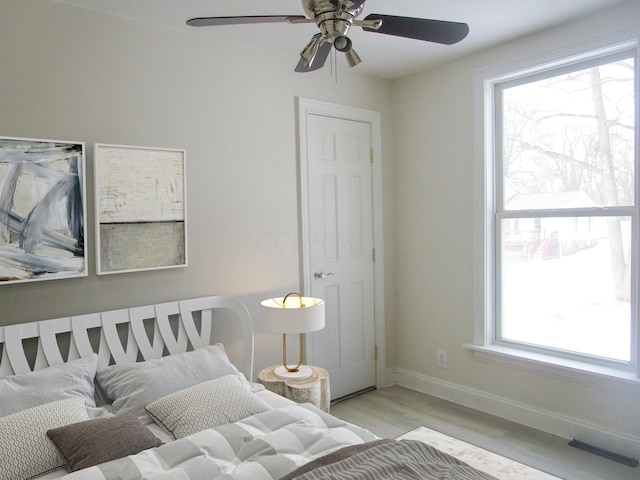 bedroom featuring light wood-style flooring, baseboards, visible vents, and ceiling fan