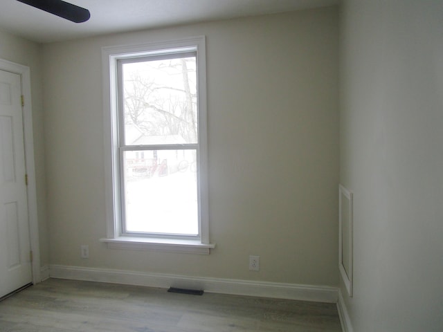 empty room featuring a ceiling fan, visible vents, light wood-style floors, and baseboards