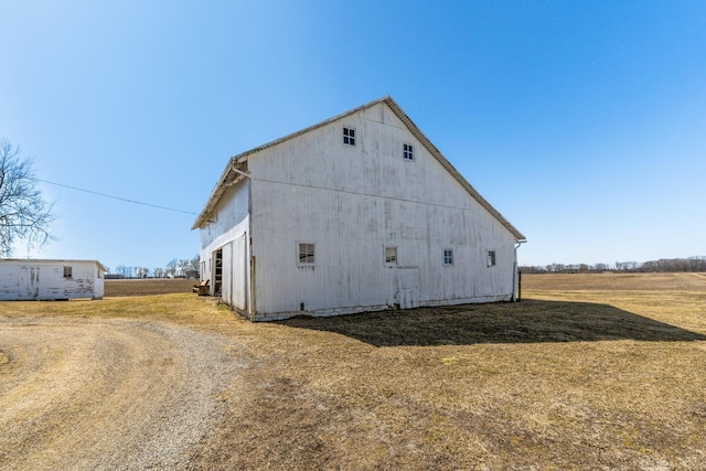 view of property exterior featuring an outbuilding, a barn, and a lawn