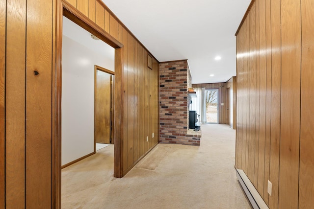 corridor featuring baseboards, light colored carpet, and wood walls