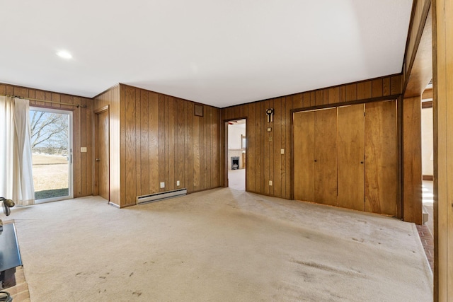 unfurnished living room featuring light carpet, baseboard heating, and wooden walls