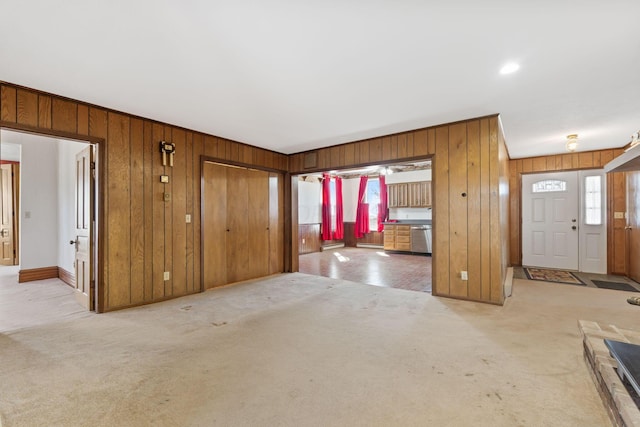 foyer entrance featuring light carpet, wooden walls, and plenty of natural light