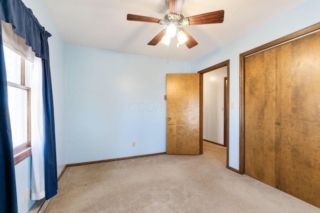 unfurnished bedroom featuring baseboards, a closet, multiple windows, and light carpet