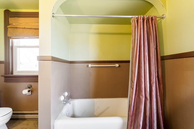 bathroom with a wainscoted wall, toilet, tile walls, and a baseboard radiator