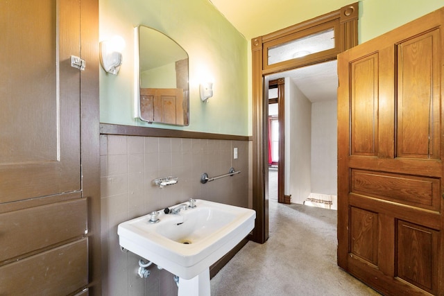 bathroom with a sink, a wainscoted wall, and tile walls