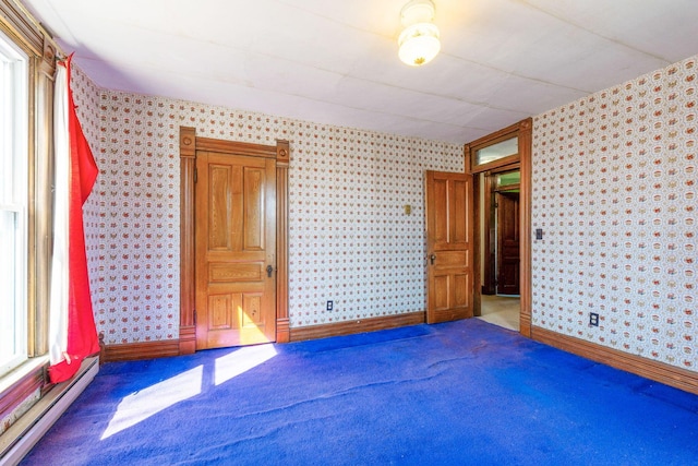 carpeted empty room with wallpapered walls, baseboards, and baseboard heating