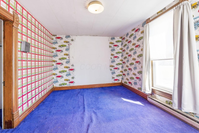 spare room with wallpapered walls, a baseboard heating unit, baseboards, and carpet floors