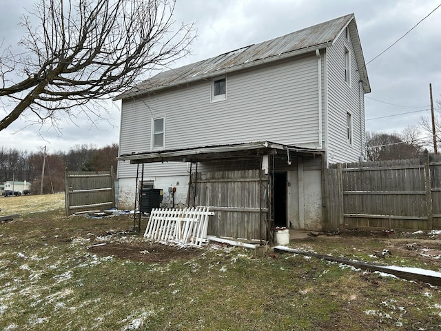 back of property with central AC unit, fence, and metal roof