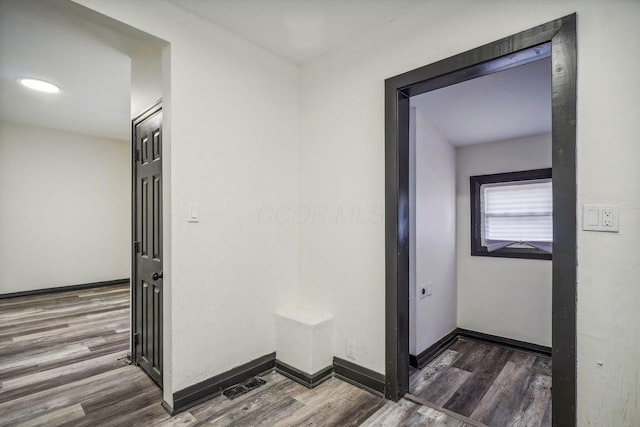 hall featuring wood finished floors, visible vents, and baseboards