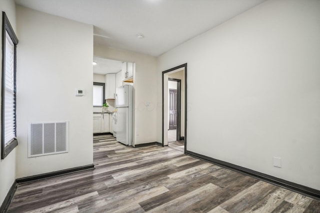 spare room featuring visible vents, baseboards, and wood finished floors