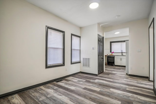 spare room with a sink, visible vents, baseboards, and wood finished floors