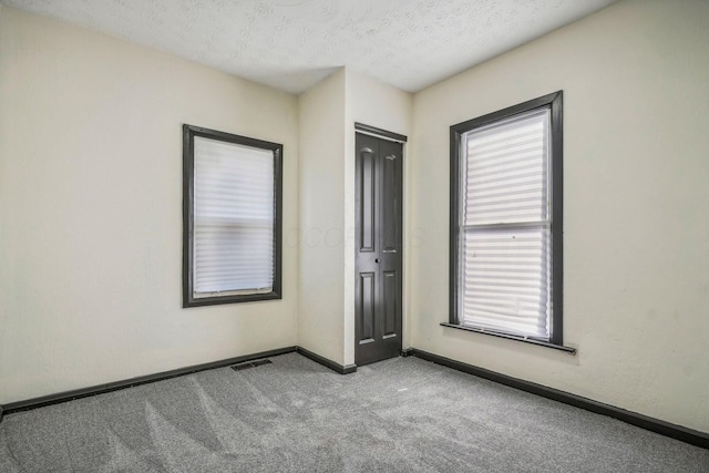 unfurnished bedroom with baseboards, visible vents, a closet, a textured ceiling, and carpet flooring