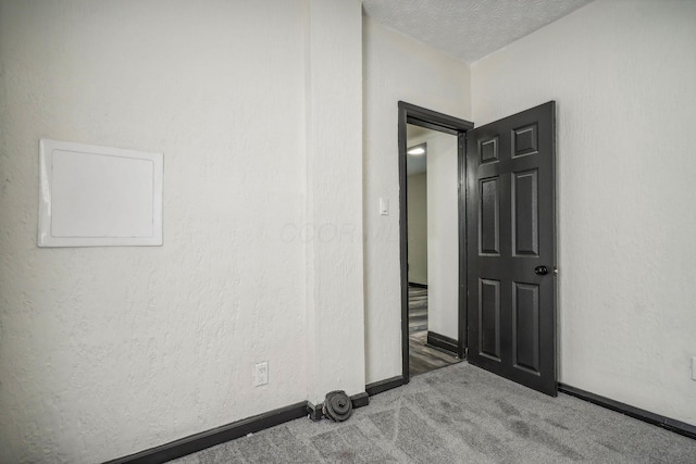 carpeted spare room with baseboards, a textured ceiling, and a textured wall