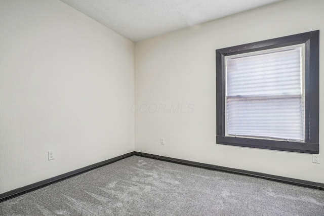 unfurnished room featuring baseboards and carpet