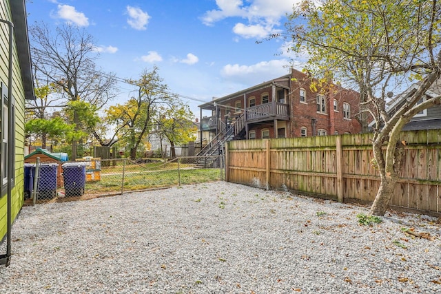 view of yard featuring gravel driveway, fence private yard, and stairs