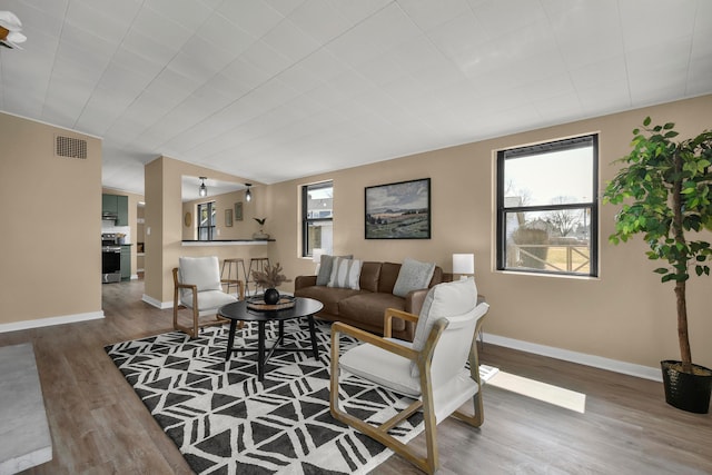 living room with wood finished floors, visible vents, and baseboards