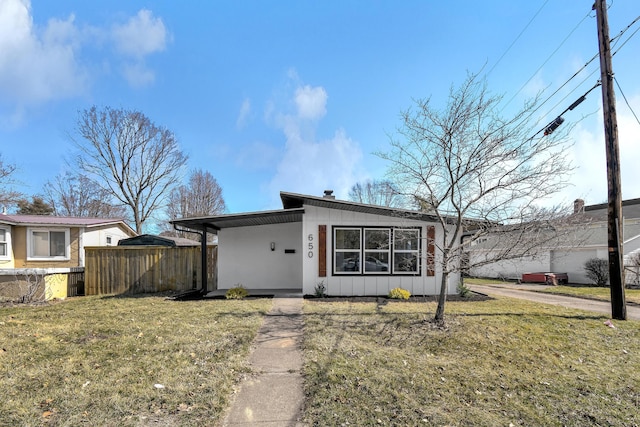 view of front of property with board and batten siding, a front lawn, and fence