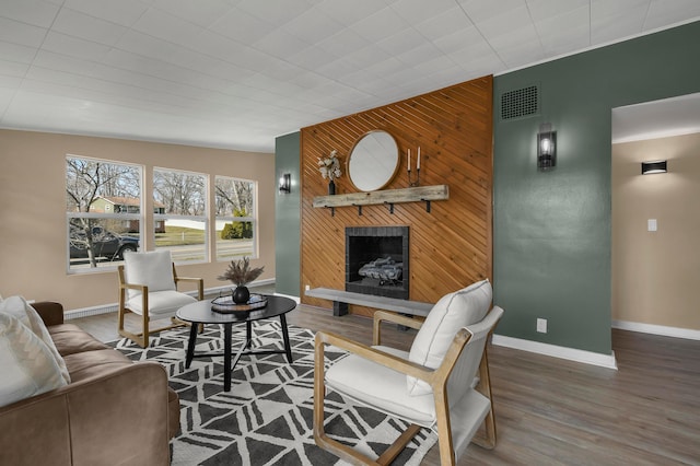 living area with visible vents, baseboards, wood finished floors, and a fireplace