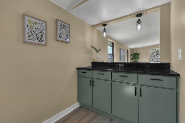 kitchen with green cabinetry, baseboards, lofted ceiling with beams, and wood finished floors