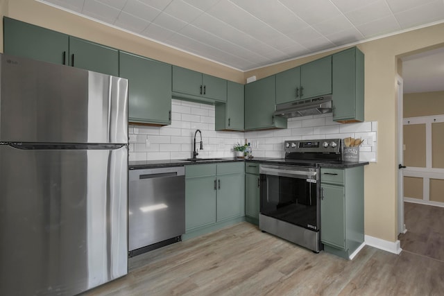 kitchen featuring under cabinet range hood, a sink, dark countertops, appliances with stainless steel finishes, and green cabinetry