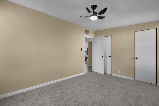 unfurnished bedroom featuring carpet, visible vents, two closets, and baseboards