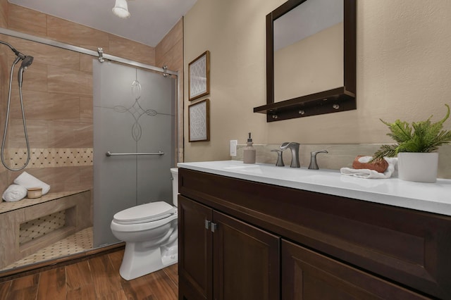 bathroom featuring vanity, a shower stall, toilet, and wood finished floors