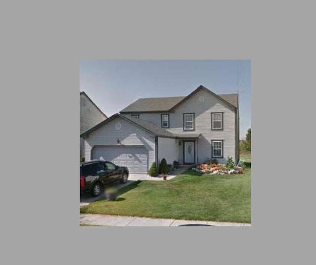 traditional-style house featuring a garage, driveway, and a front yard