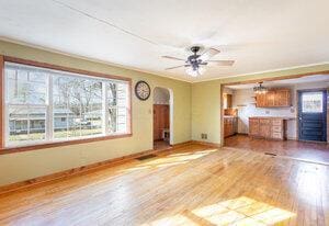 unfurnished living room featuring crown molding, ceiling fan, baseboards, wood finished floors, and arched walkways