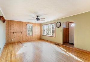 empty room with wood finished floors, a ceiling fan, and crown molding