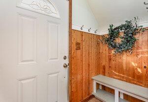 mudroom with wood walls and lofted ceiling