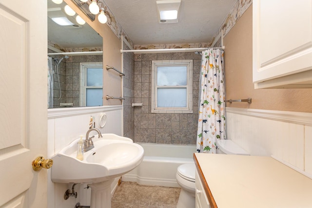 full bathroom featuring toilet, wainscoting, shower / tub combo, tile patterned floors, and a textured ceiling