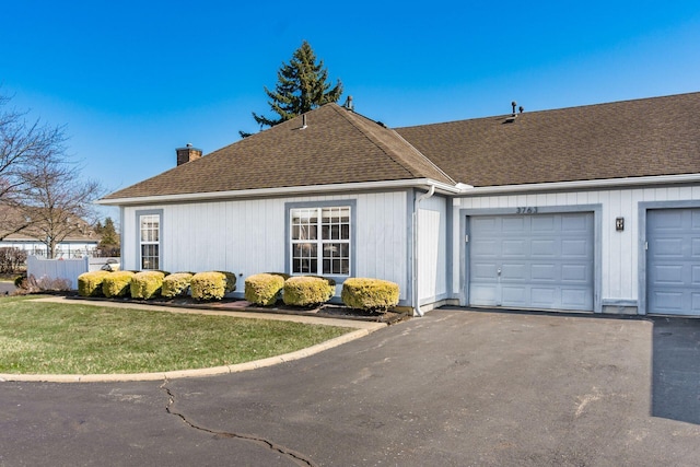 single story home featuring a shingled roof, aphalt driveway, a front yard, a chimney, and an attached garage