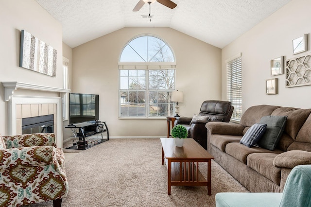 carpeted living area with lofted ceiling, a ceiling fan, a textured ceiling, baseboards, and a tile fireplace