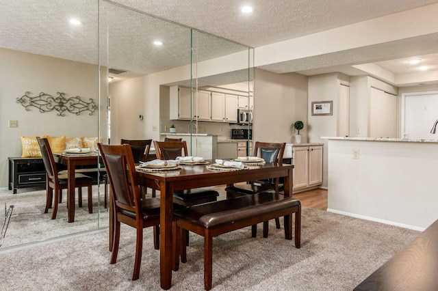 dining area with baseboards, light carpet, and a textured ceiling