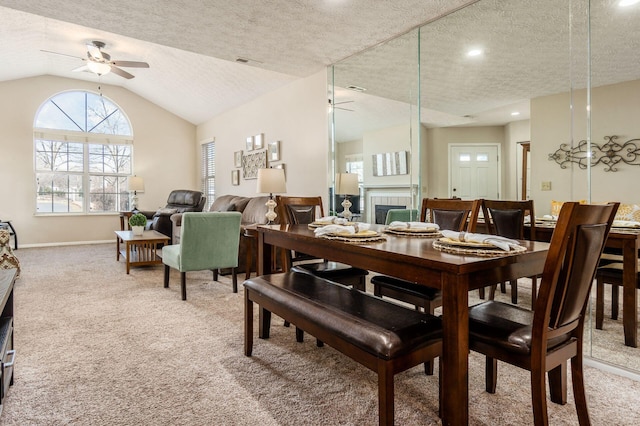 dining space with light carpet, a textured ceiling, lofted ceiling, and a ceiling fan